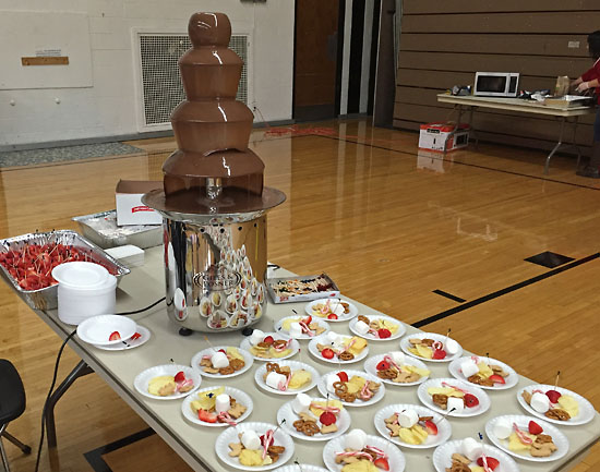 The chocolate fountain with strawberries, potato chips, pretzels, animal crackers, and candy canes for dipping.